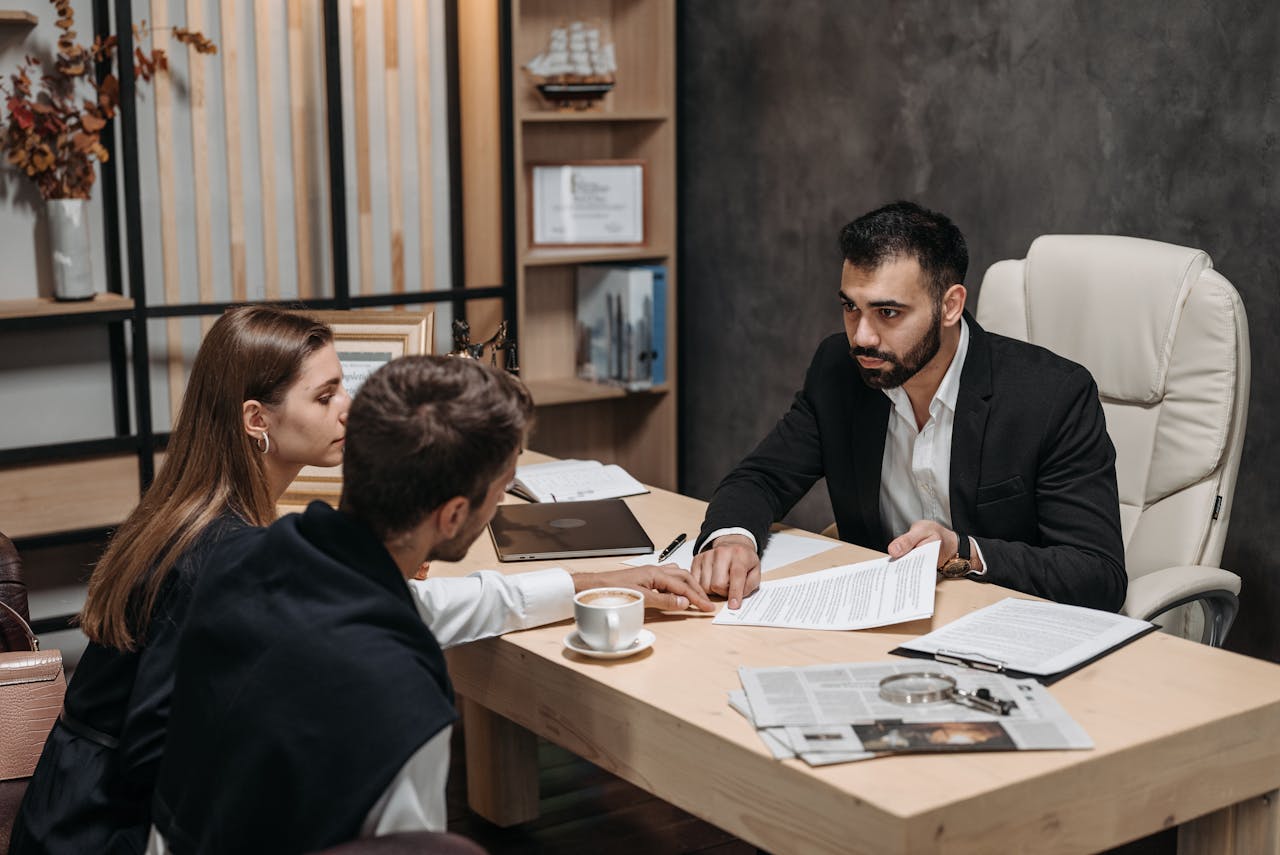 about-01 Lawyer discussing legal documents with clients at office desk.